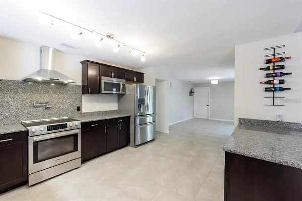 a large kitchen with stainless steel appliances granite countertop a sink stove and refrigerator