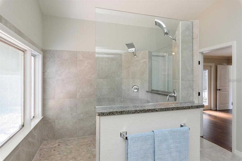 5002 Southeast 7th Place Ocala, FL 34471 - Photo 18 of 30 a bathroom with a granite countertop sink a mirror and a shower