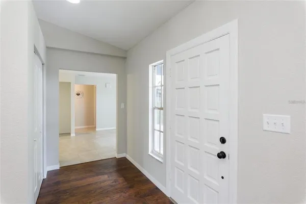 a view of an empty room with wooden floor and a kitchen