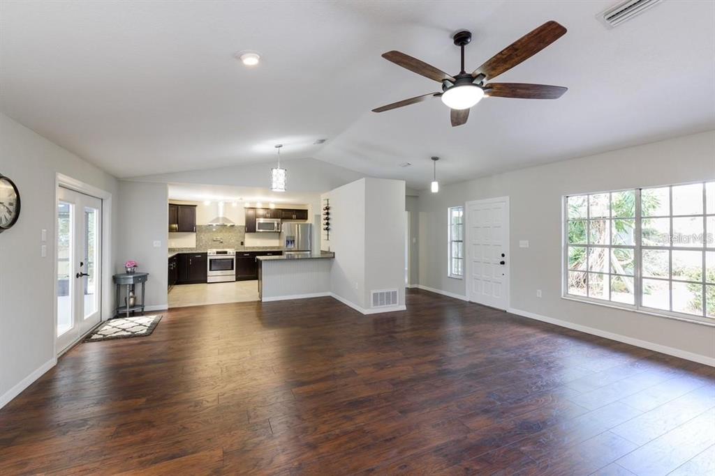 5002 Southeast 7th Place Ocala, FL 34471 - Photo 9 of 30 a view of an empty room with wooden floor and a kitchen
