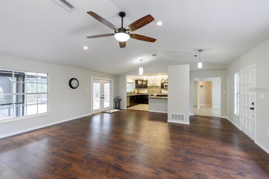 5002 Southeast 7th Place Ocala, FL 34471 - Photo 10 of 30 an empty room with wooden floor a ceiling fan and windows