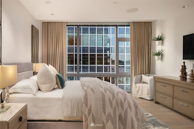 a bedroom with a bed and a flat tv screen next to a window
