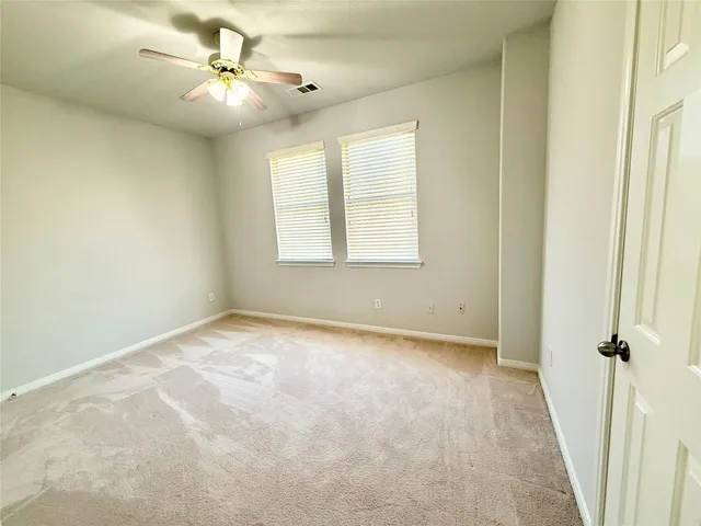 an empty room with windows and fan