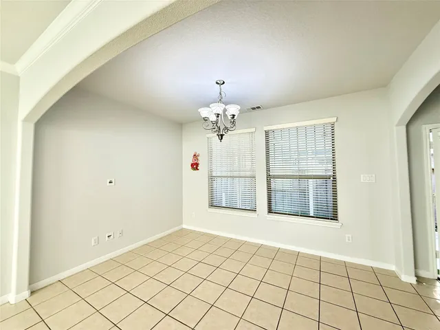 a view of an empty room with chandelier fan