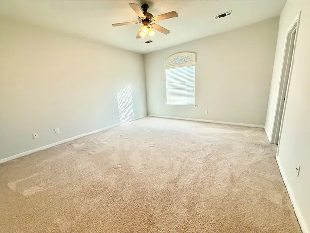 an empty room with windows and fan