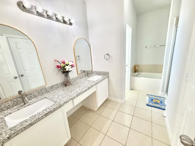 a spacious bathroom with a granite countertop sink a mirror and bathtub