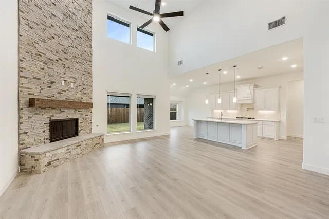 a view of an empty room and kitchen with fireplace wooden floor