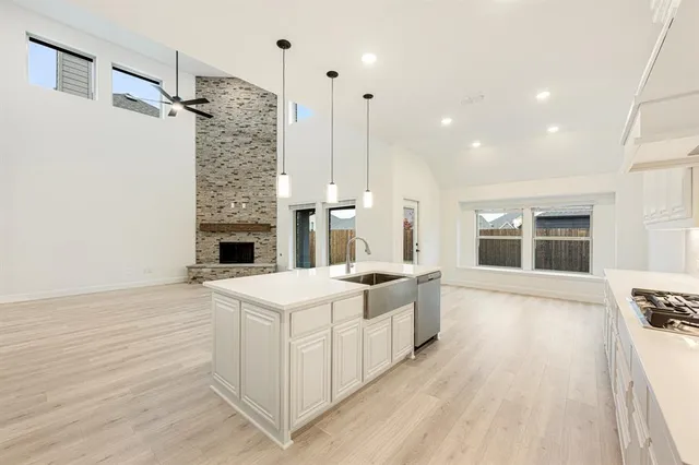 a large white kitchen with a stove a sink dishwasher and a fireplace with wooden floor