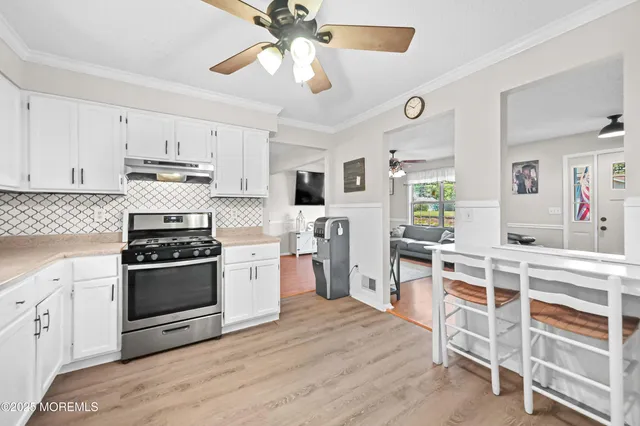 a kitchen with stainless steel appliances white cabinets and wooden floor