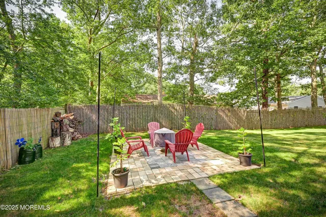 a view of backyard with table and chairs potted plants and large trees