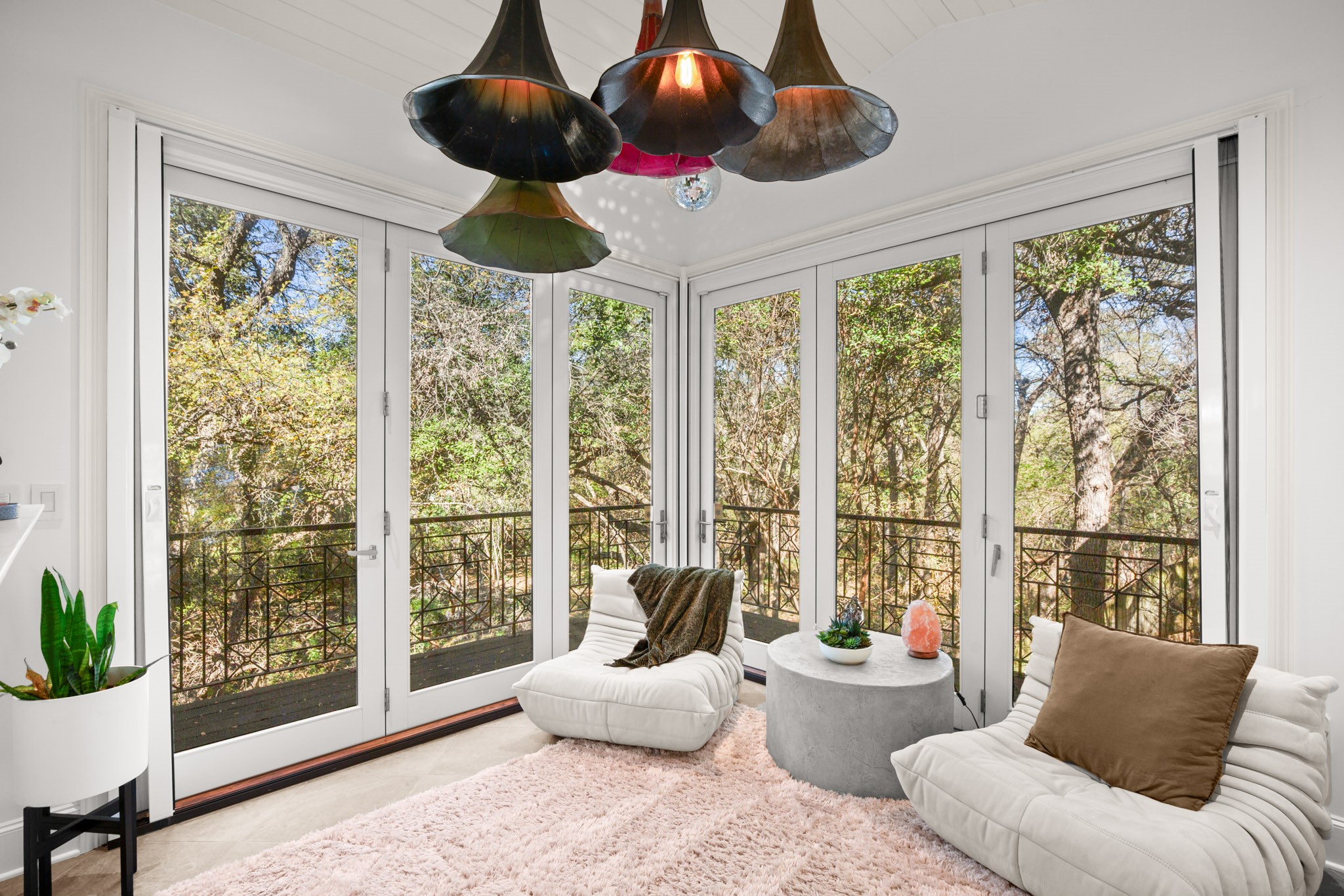 Floor-to-ceiling French doors open to a serene, tree-lined view, creating a peaceful indoor-outdoor ambiance.
