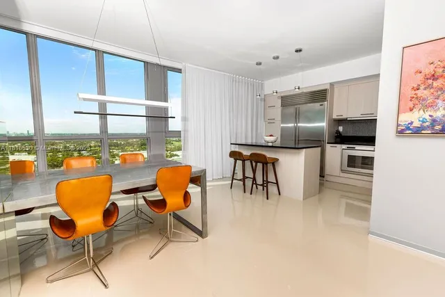 a kitchen with stainless steel appliances kitchen island granite countertop a table chairs and a refrigerator