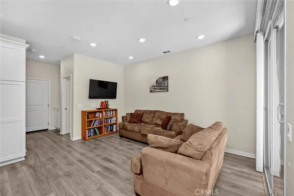 a kitchen with stainless steel appliances granite countertop a stove top oven a sink dishwasher a refrigerator and a dining table with wooden floor