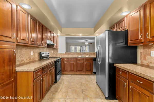 a kitchen with stainless steel appliances granite countertop a refrigerator a sink dishwasher and wooden cabinets