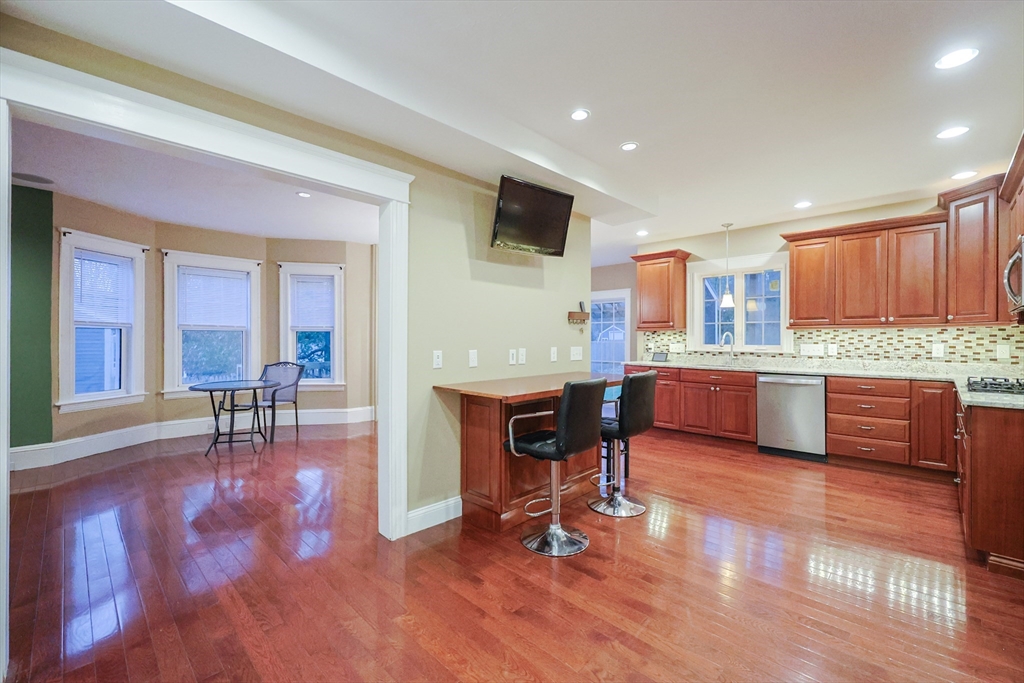 11 Hockanum Way Worcester, MA 01606 - Photo 5 of 36 a open kitchen with stainless steel appliances kitchen island granite countertop a refrigerator a stove a sink a dining table and chairs with wooden floor
