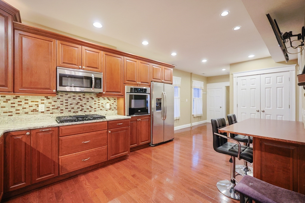 11 Hockanum Way Worcester, MA 01606 - Photo 7 of 36 a large kitchen with stainless steel appliances wooden floors and wooden cabinets