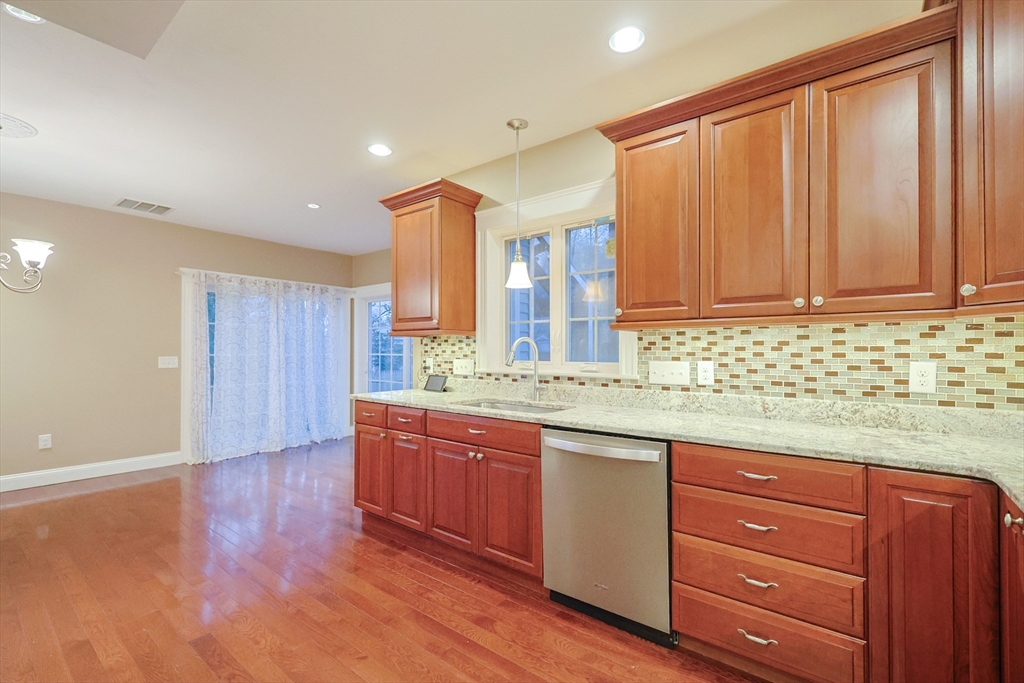 11 Hockanum Way Worcester, MA 01606 - Photo 8 of 36 a kitchen with granite countertop wooden cabinets a sink and dishwasher with wooden floor