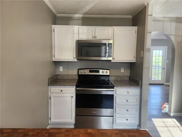 a kitchen with granite countertop white cabinets and stainless steel appliances