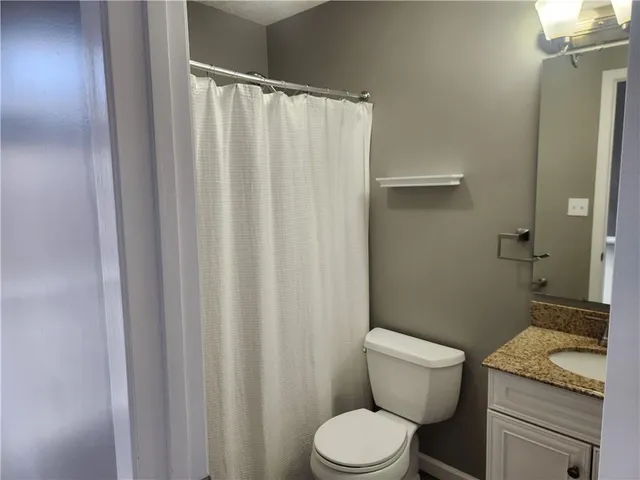 a bathroom with a granite countertop toilet and a sink