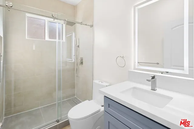 a bathroom with a sink toilet vanity and shower