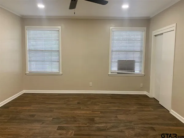 a view of an empty room with wooden floor and a window