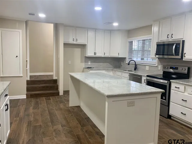 a kitchen with granite countertop a sink and a stove top oven