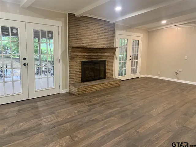an empty room with wooden floor fireplace and windows