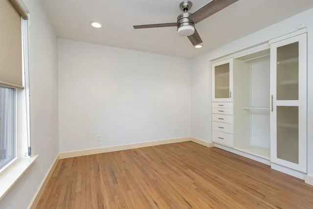 an empty room with wooden floor cabinet and windows
