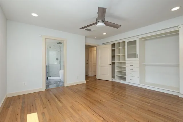 an empty room with wooden floor closet and windows