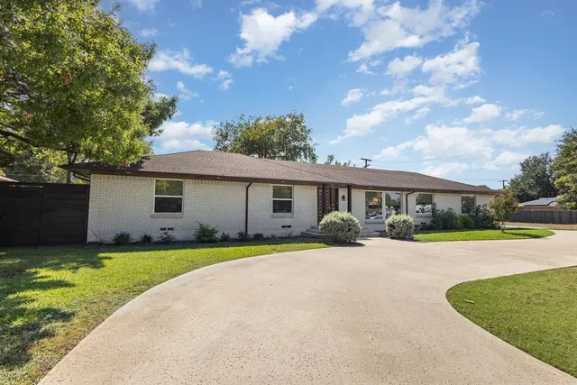 a front view of a house with a garden and trees