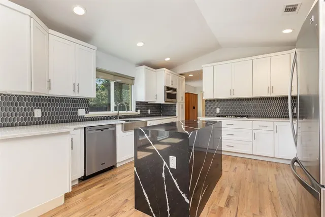 a kitchen with granite countertop white cabinets sink and stainless steel appliances