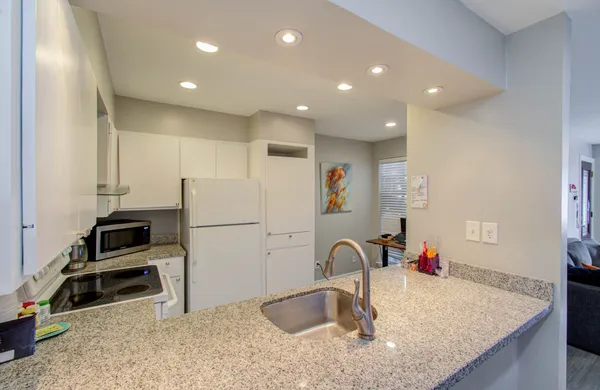 a kitchen with kitchen island granite countertop a sink a stove and a refrigerator
