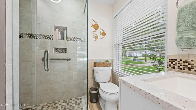 a bathroom with a granite countertop sink a toilet and shower