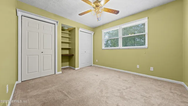an empty room with closet and fan