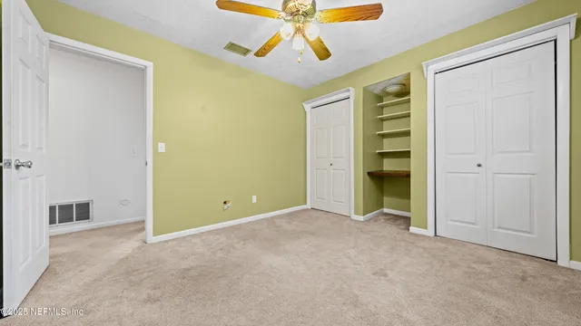 an empty room with closet and a ceiling fan