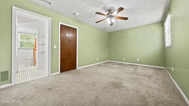 an empty room with a chandelier fan and windows