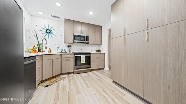 a kitchen with stainless steel appliances a sink cabinets and wooden floor