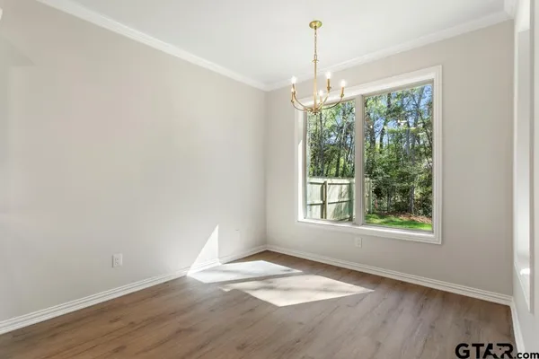 an empty room with wooden floor a chandelier and windows