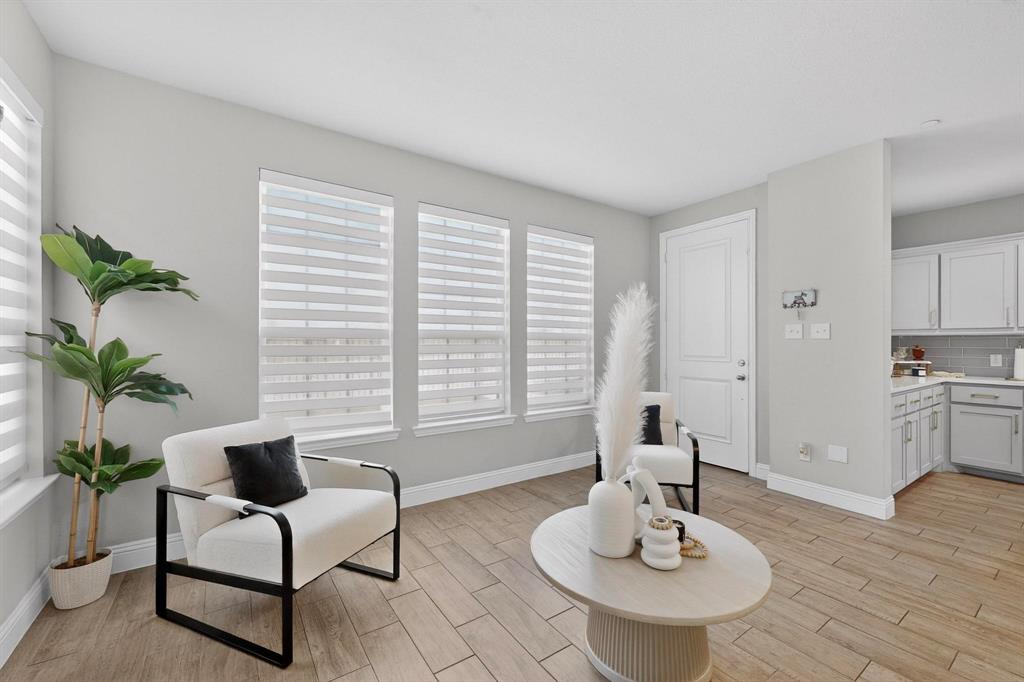 6040 Bursey Road Watauga, TX 76148 - Photo 17 of 39 Living area featuring three windows with blinds, light-colored walls, and wood-look flooring