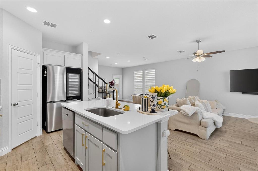 6040 Bursey Road Watauga, TX 76148 - Photo 18 of 39 The open concept living area features light-colored flooring, a kitchen island with a sink and white countertop, and recessed lighting