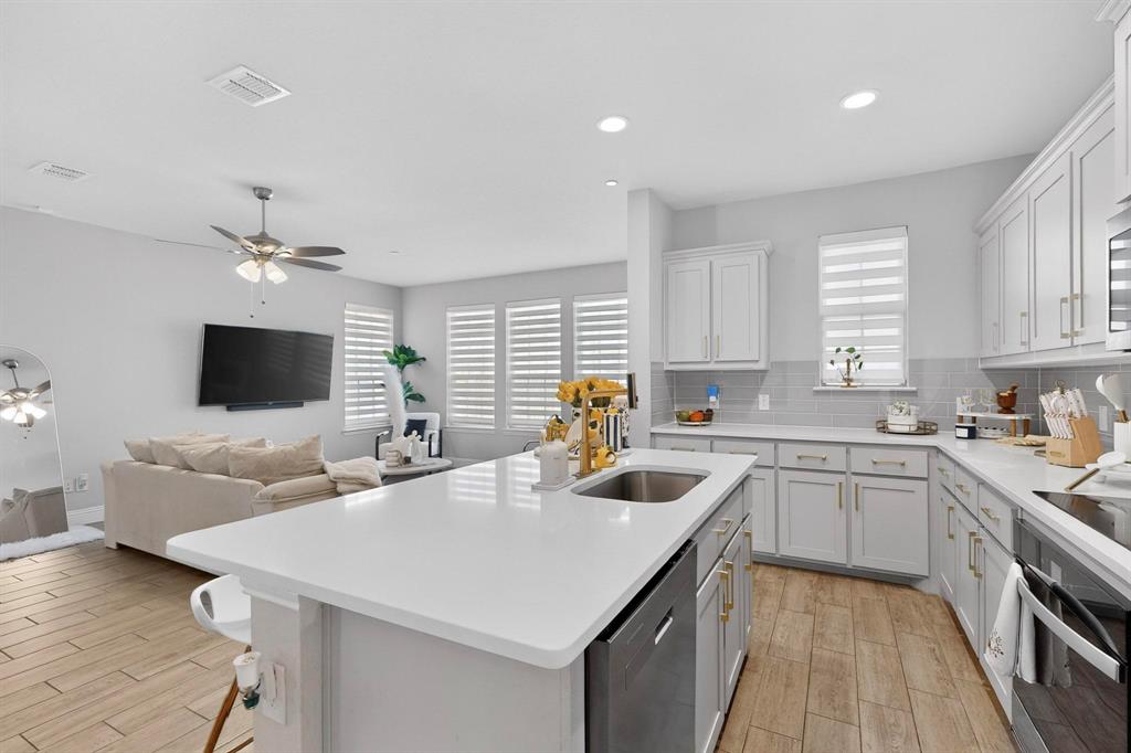 6040 Bursey Road Watauga, TX 76148 - Photo 19 of 39 The kitchen features white cabinetry, light countertops, and a stainless steel sink with a gold-toned faucet