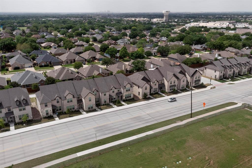 6040 Bursey Road Watauga, TX 76148 - Photo 2 of 39 Aerial view showcasing a row of properties with light-colored exteriors and dark roofs, situated along a paved road