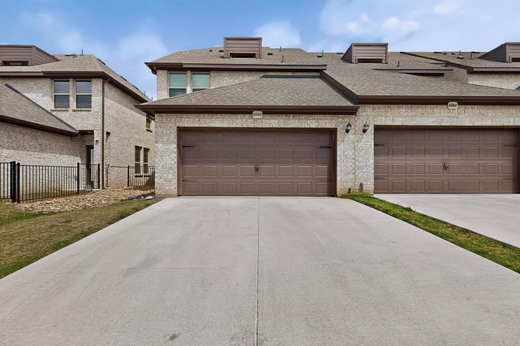 6040 Bursey Road Watauga, TX 76148 - Photo 32 of 39 The property features a light-colored brick exterior with brown garage doors and a grey roof
