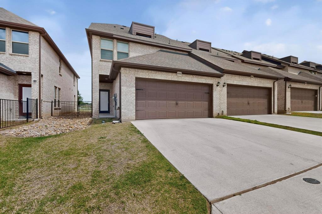 6040 Bursey Road Watauga, TX 76148 - Photo 33 of 39 The property features a light-colored brick exterior with brown garage doors and a paved driveway