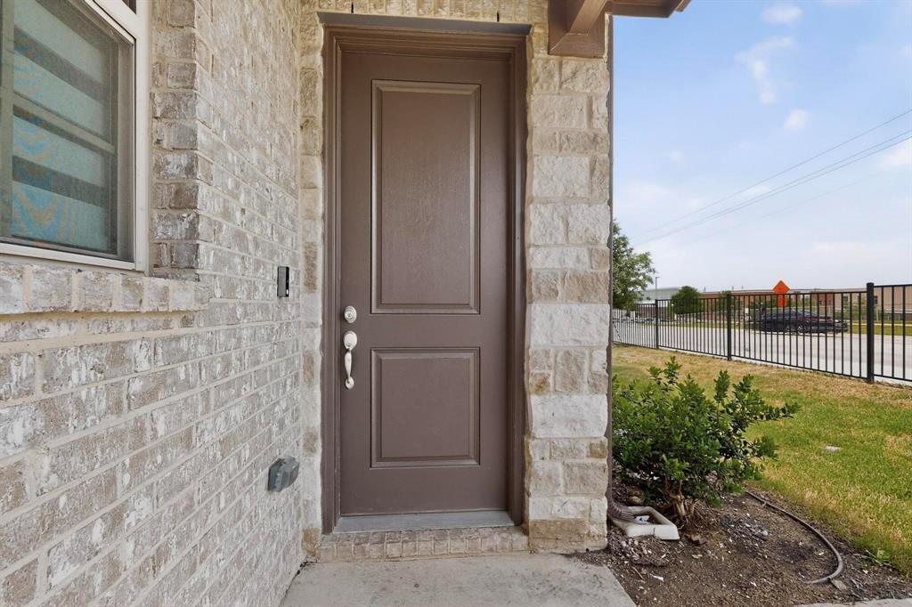 6040 Bursey Road Watauga, TX 76148 - Photo 10 of 39 The property features an entryway with a panel door, brick and stone exterior, and a small shrub