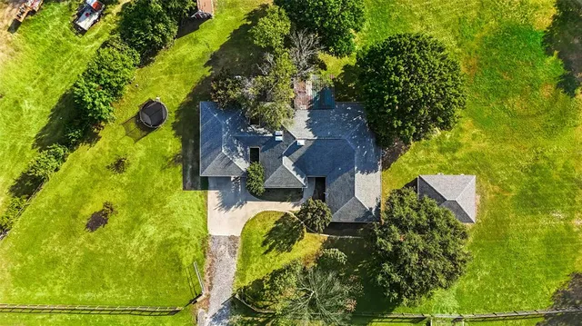 an aerial view of a house with swimming pool and large trees