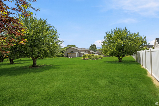 580 North 300 East Logan, UT 84321 - Photo 72 of 74 Expansive green lawn with mature trees, a white perimeter fence, and distant residential structures