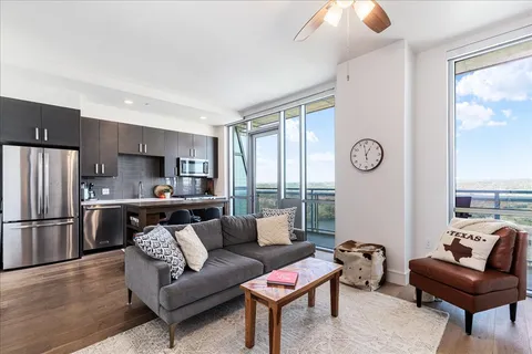a living room with furniture a large window and stainless steel appliances