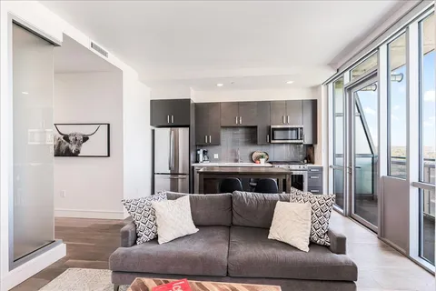 a living room with stainless steel appliances furniture and a kitchen view