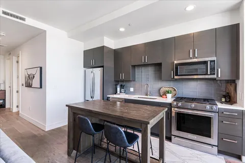 a kitchen with stainless steel appliances a stove a sink a microwave a refrigerator and cabinets